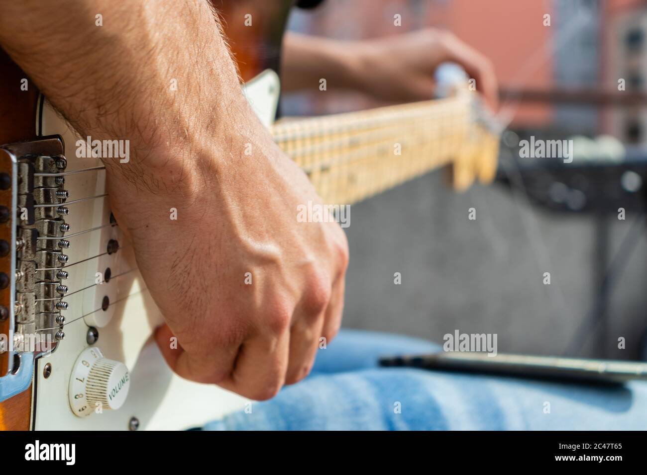 Close-up of guitar player as he is tuning his guitar before concert. Stock Photo