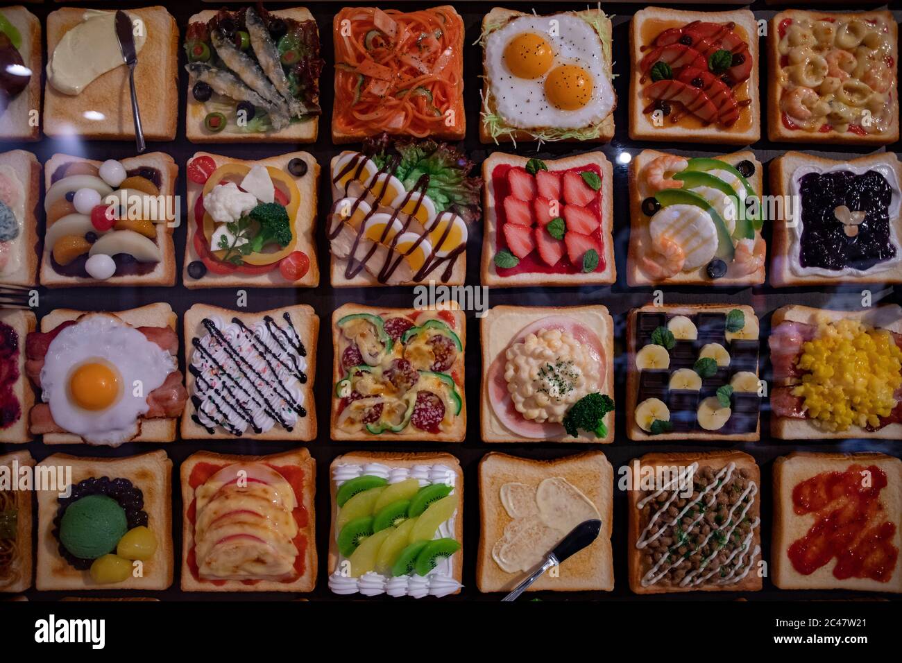 Close-up on toast with various dressing. Artificial food made by wax. Shop window display, restaurant menu food sample. Stock Photo