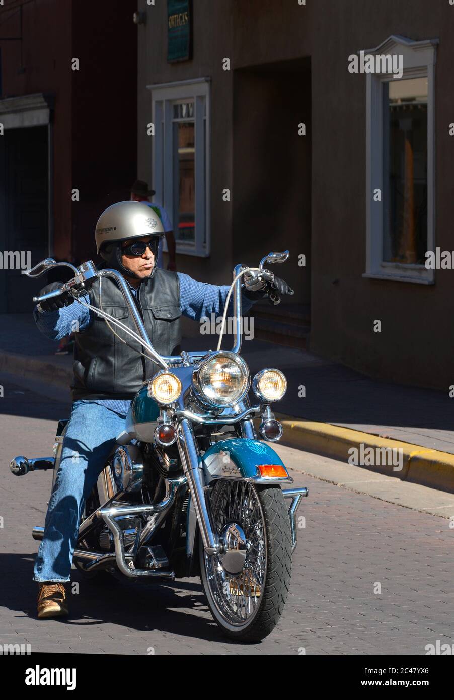 A man riding a customized Harley-Davidson motorcycle with ape hanger handlebars rides along a street in Santa Fe, New Mexico. Stock Photo