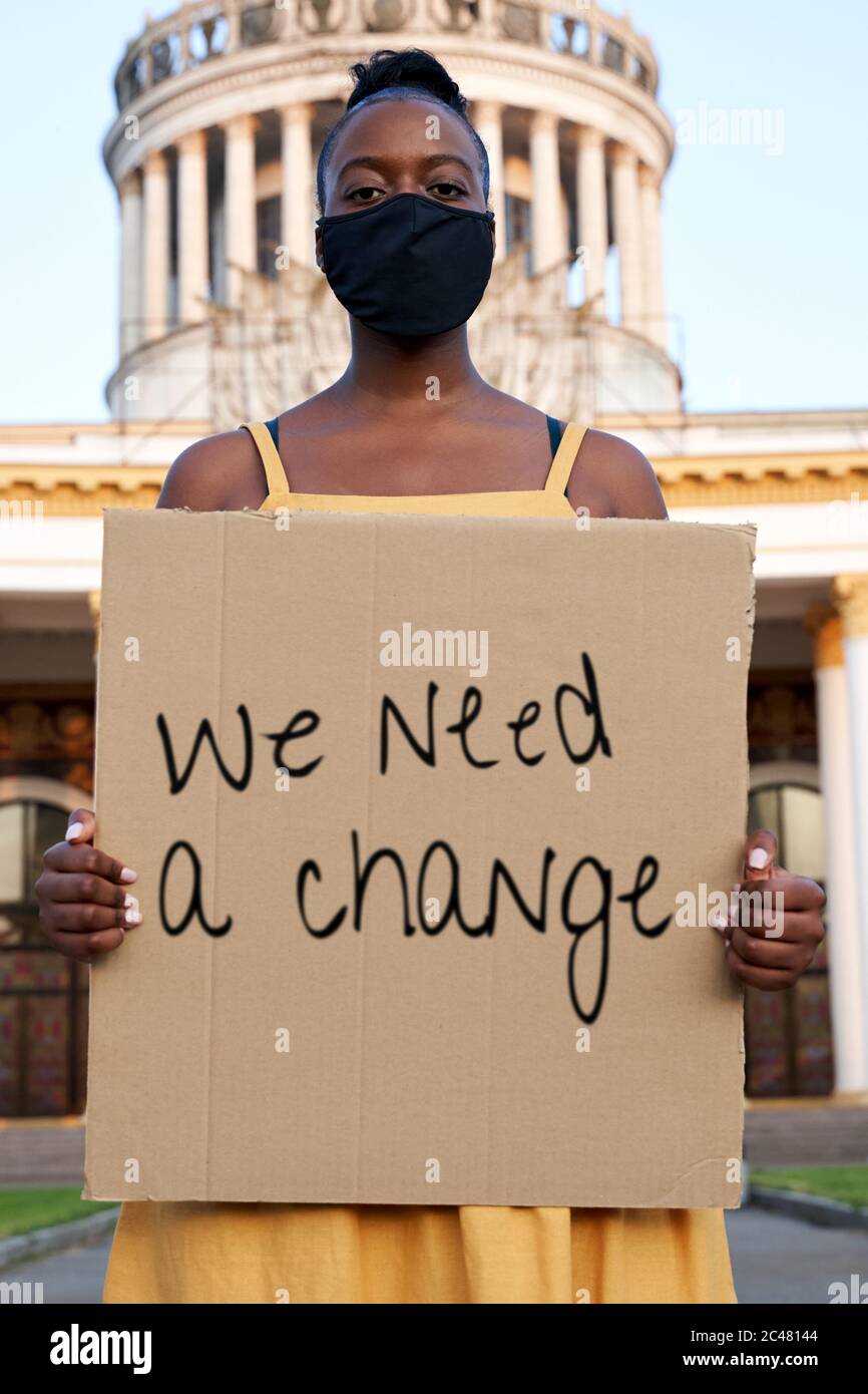 Young african woman wear black face mask stand outdoors holding sign protesting. Stock Photo