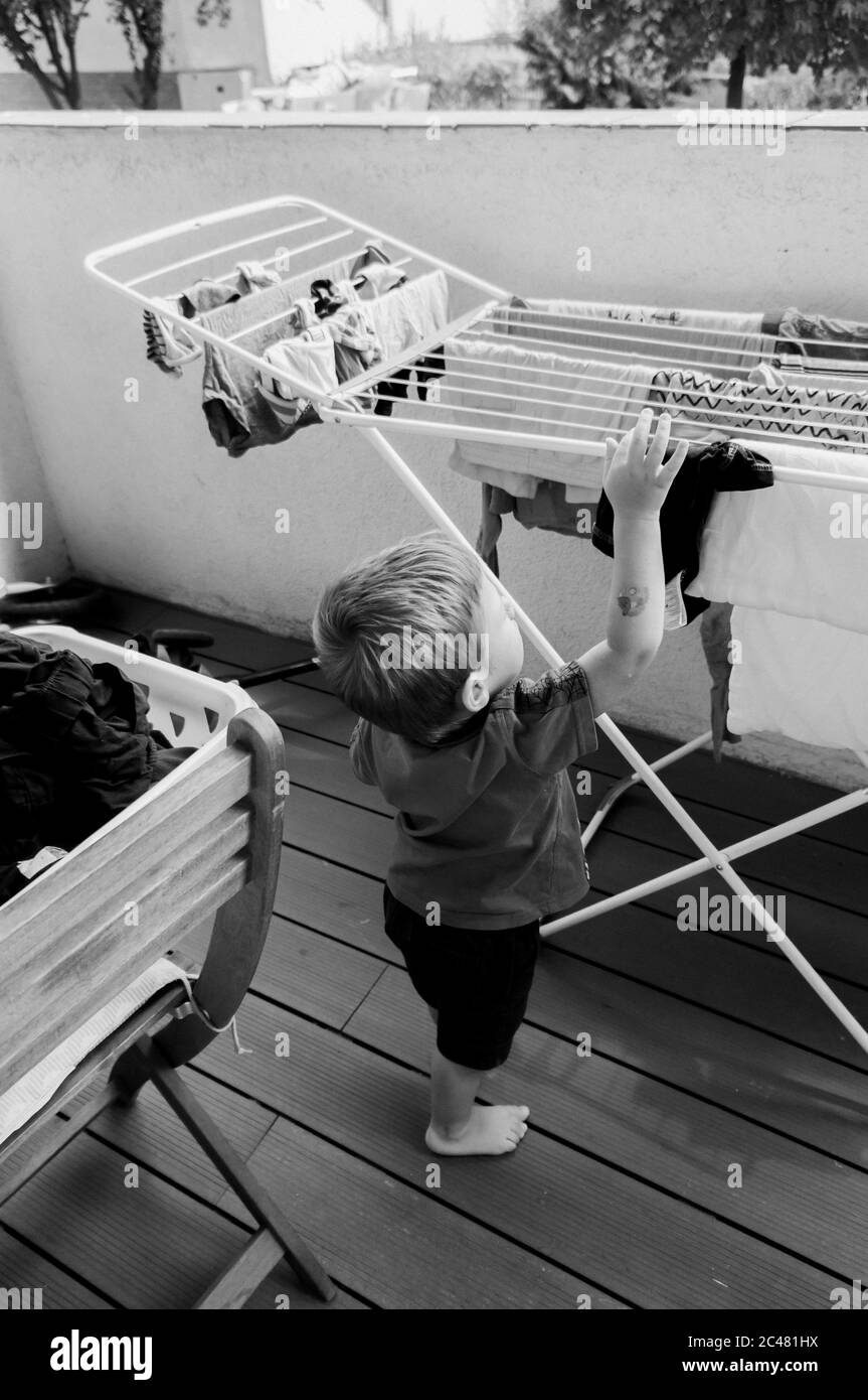 POZNAN, POLAND Jul 31, 2019 Two years old Polish Caucasian boy hanging laundry at a balcony