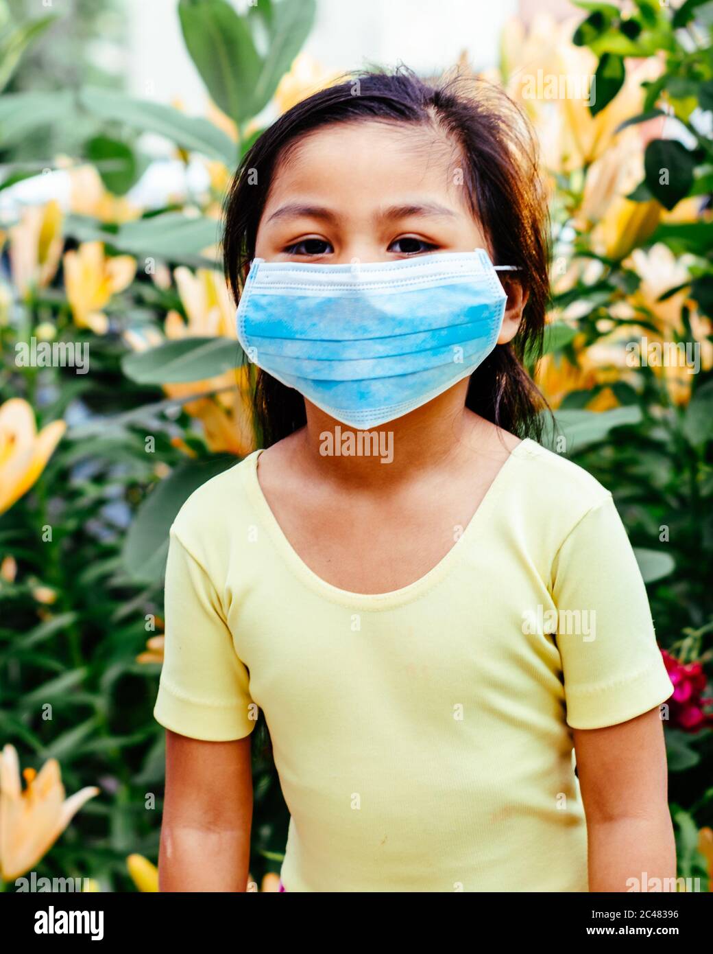 Mexican American girl is wearing a blue face mask while outdoors Stock Photo