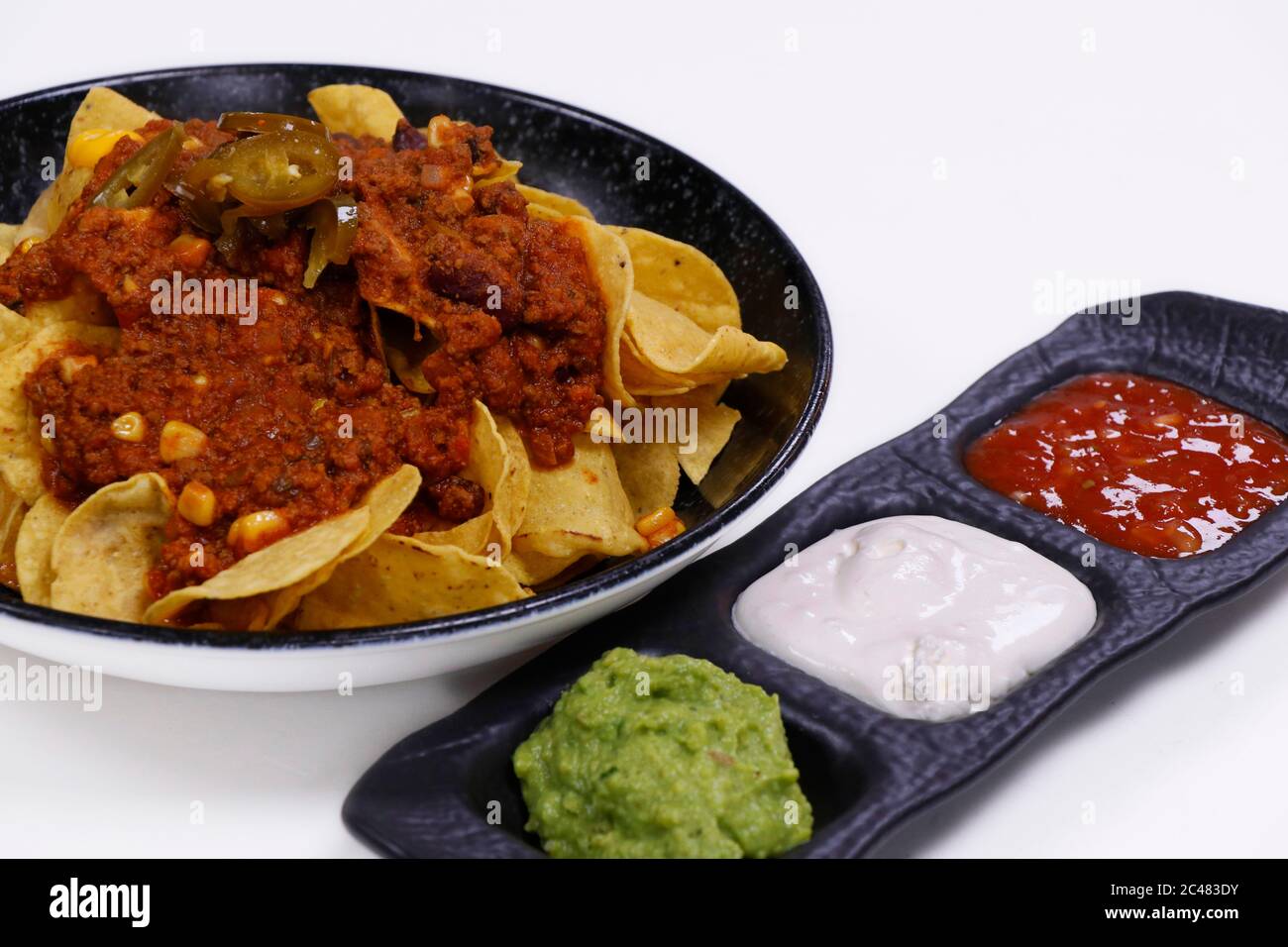 mexican nachos chips with chili beef, avocado, sour cream and tomato salsa Stock Photo