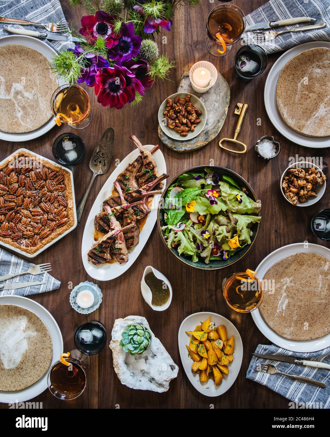 Tablescape with lamb, spring salad, golden beets, mixed drinks, and pecan pie Stock Photo