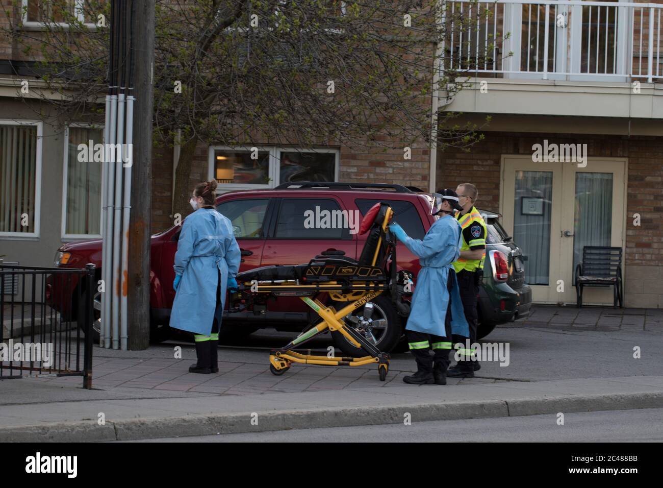 Stretcher taken out of ambulance by paramedics wearing personal protective gear and medical gowns. Medical gurney ready to transport sick patients. Stock Photo