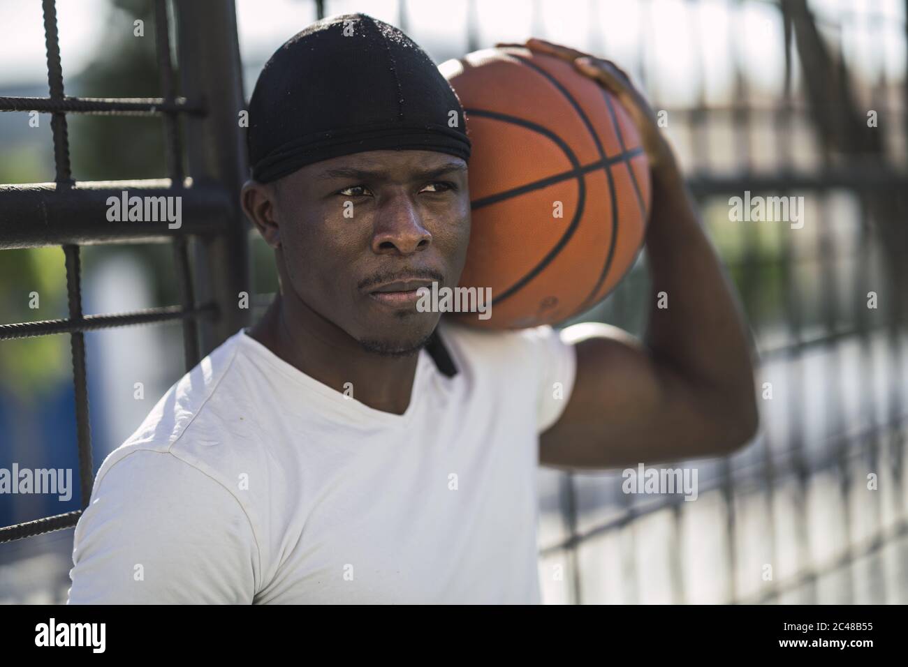 Closeup shot of an African-American male in a white shirt carrying the ball on his shoulder Stock Photo