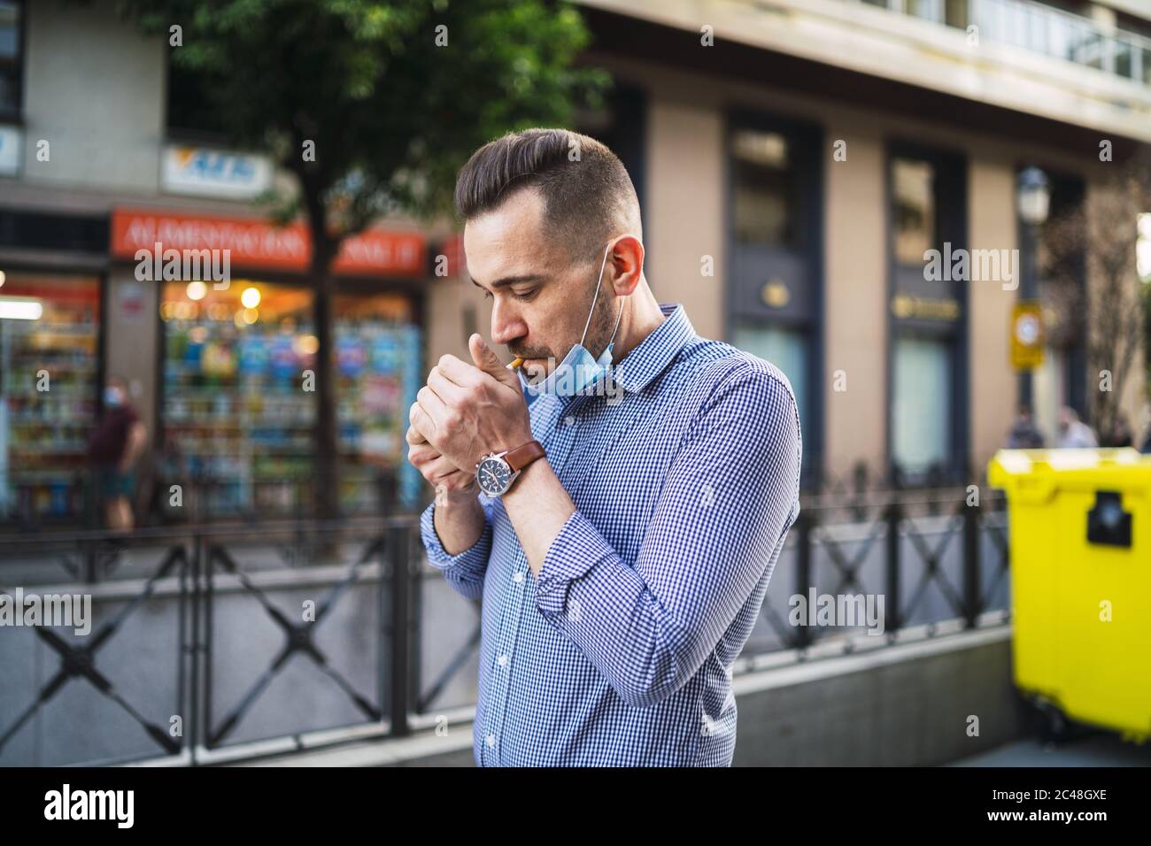 Young male with a medical face mask smoking a cigarette on the street