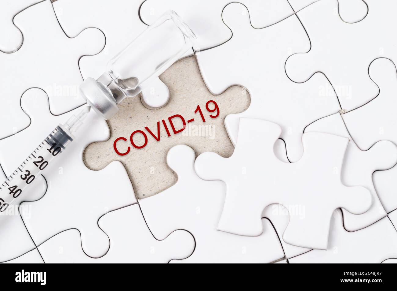 Vaccine and syringe injection with COVID-19 text on jigsaw. Prevention, immunization and treatment from corona virus infection.  Medicine infectious c Stock Photo