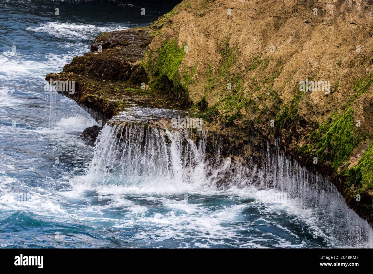 Water cascading back into the ocean after a wave breaks on the rocky ...