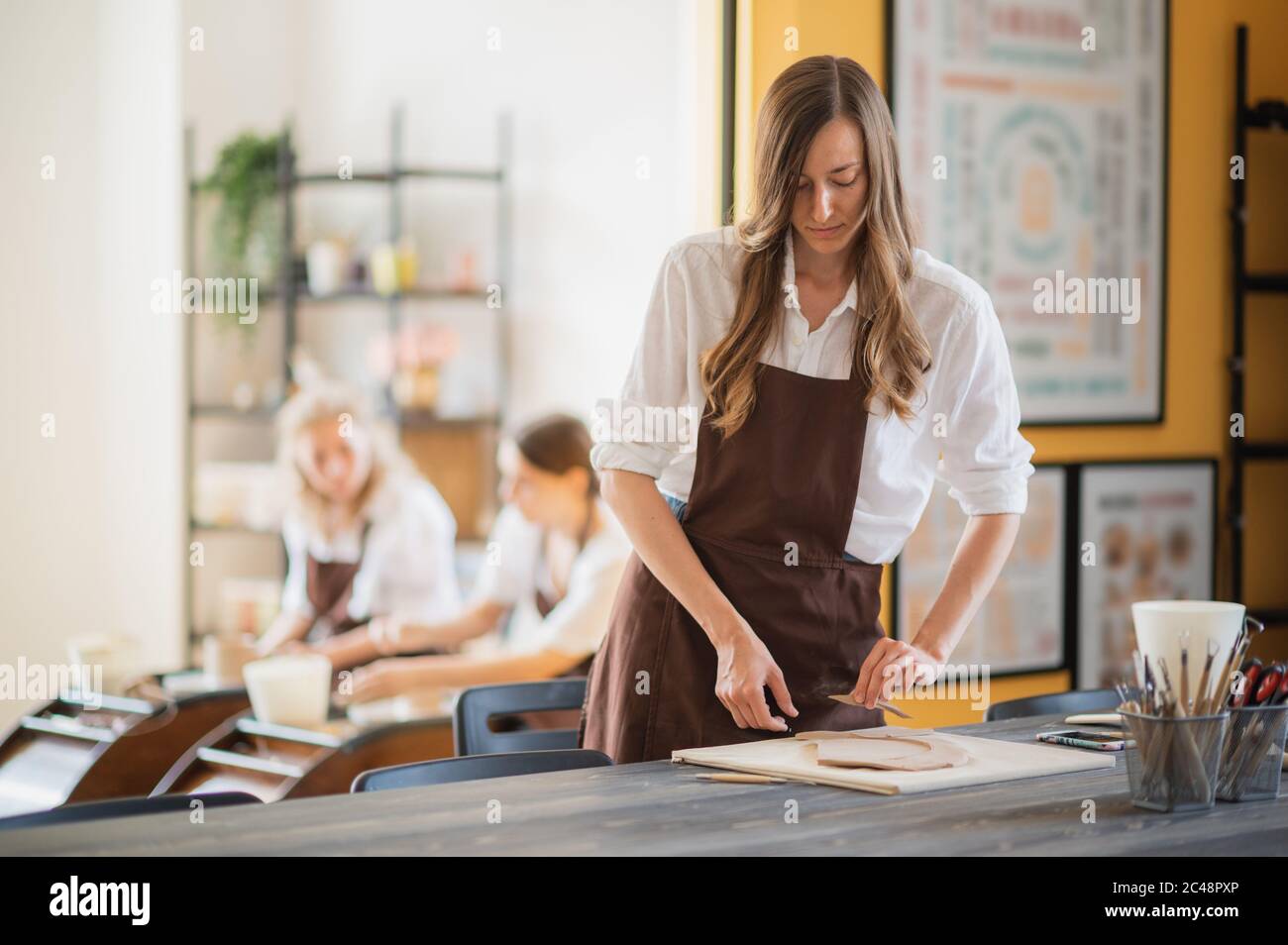 Women working In pottery studio, smiling and talking. Ceramic workshop, pottery master class. Stock Photo