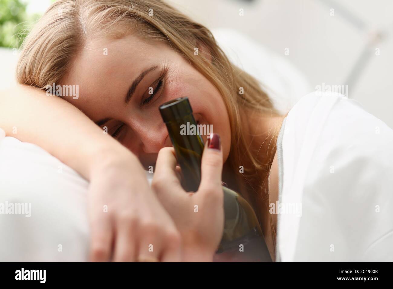 Cheerful young woman with wine waking up after night party Stock Photo