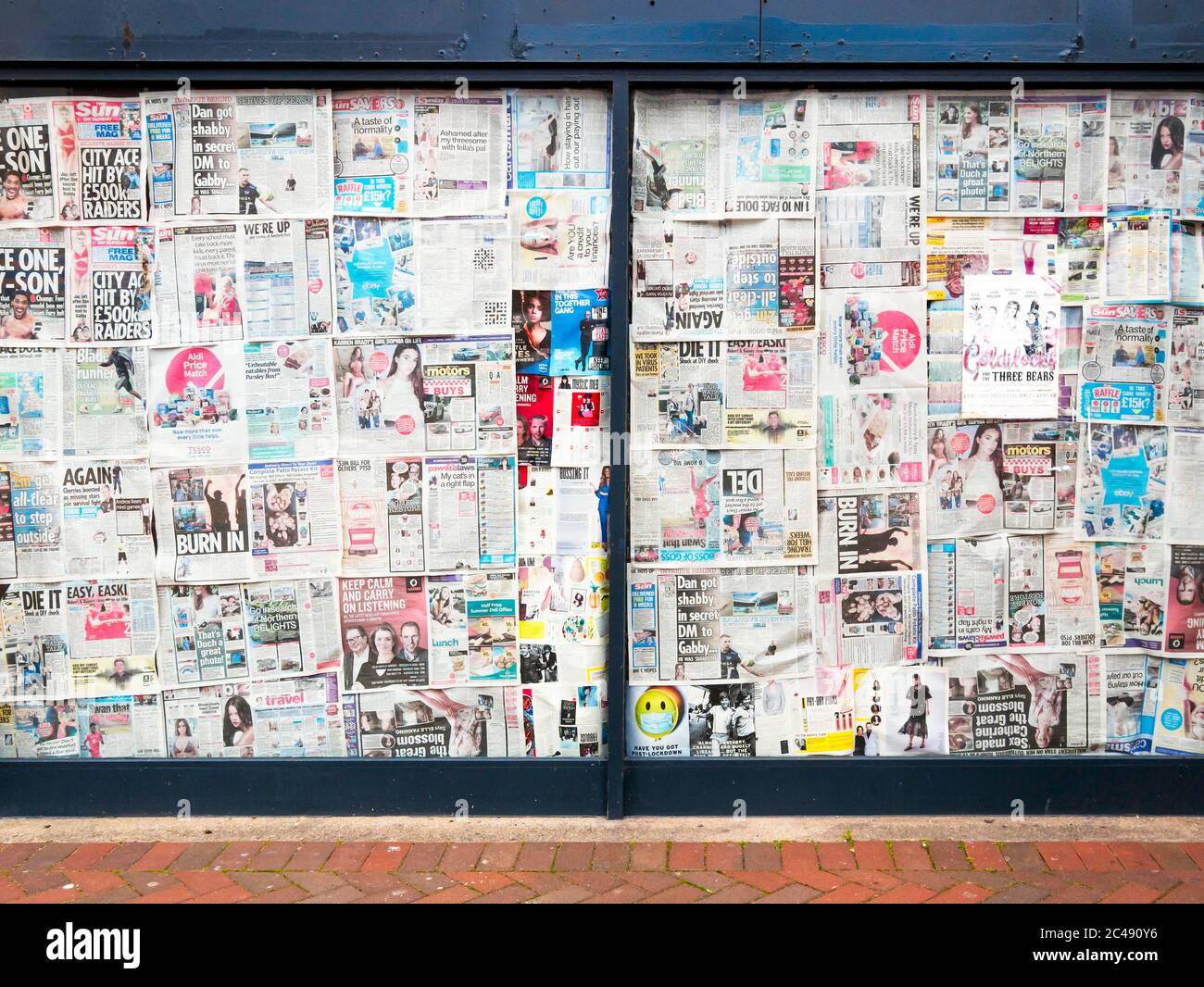 Window of an empty shop with the window obscured using old newspapers Stock Photo