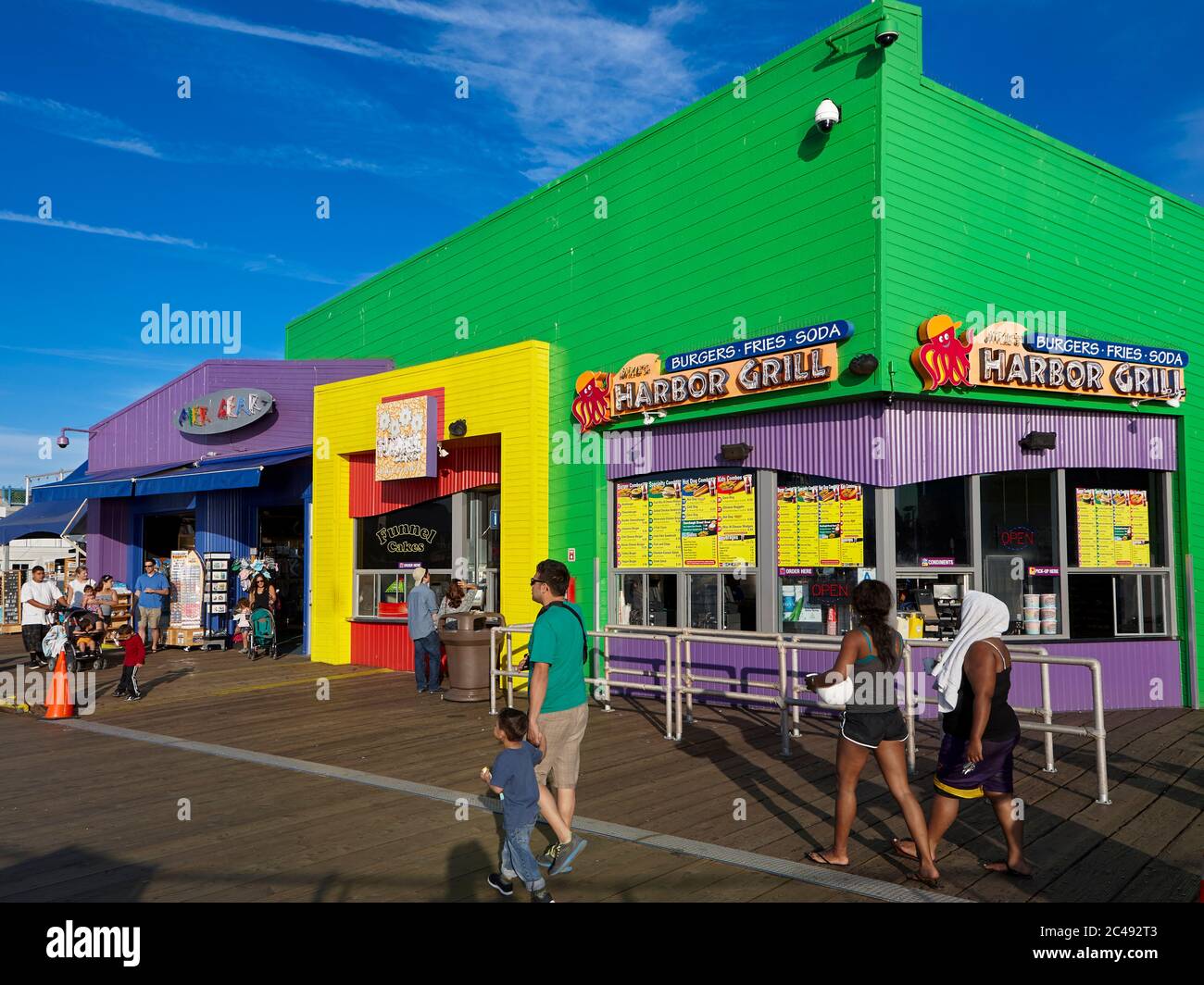 People walk by the colorful building of the Harbor Grill restaurant on the Santa Monica Pier. Santa Monica, Los Angeles, California, USA. Stock Photo