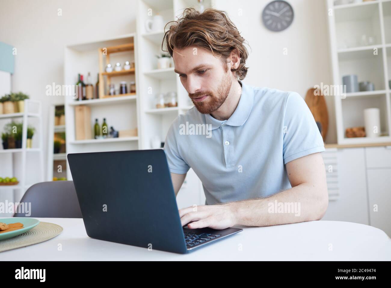 Young man sitting at the table and using laptop computer at home Stock Photo
