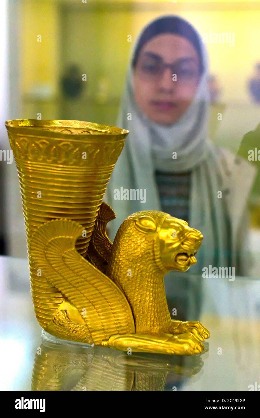 Iranian Muslim woman admires Achaemenid Persian Lion Rhyton vase landmark archaeological piece from 5th Century BC, Tehran, Iran Stock Photo
