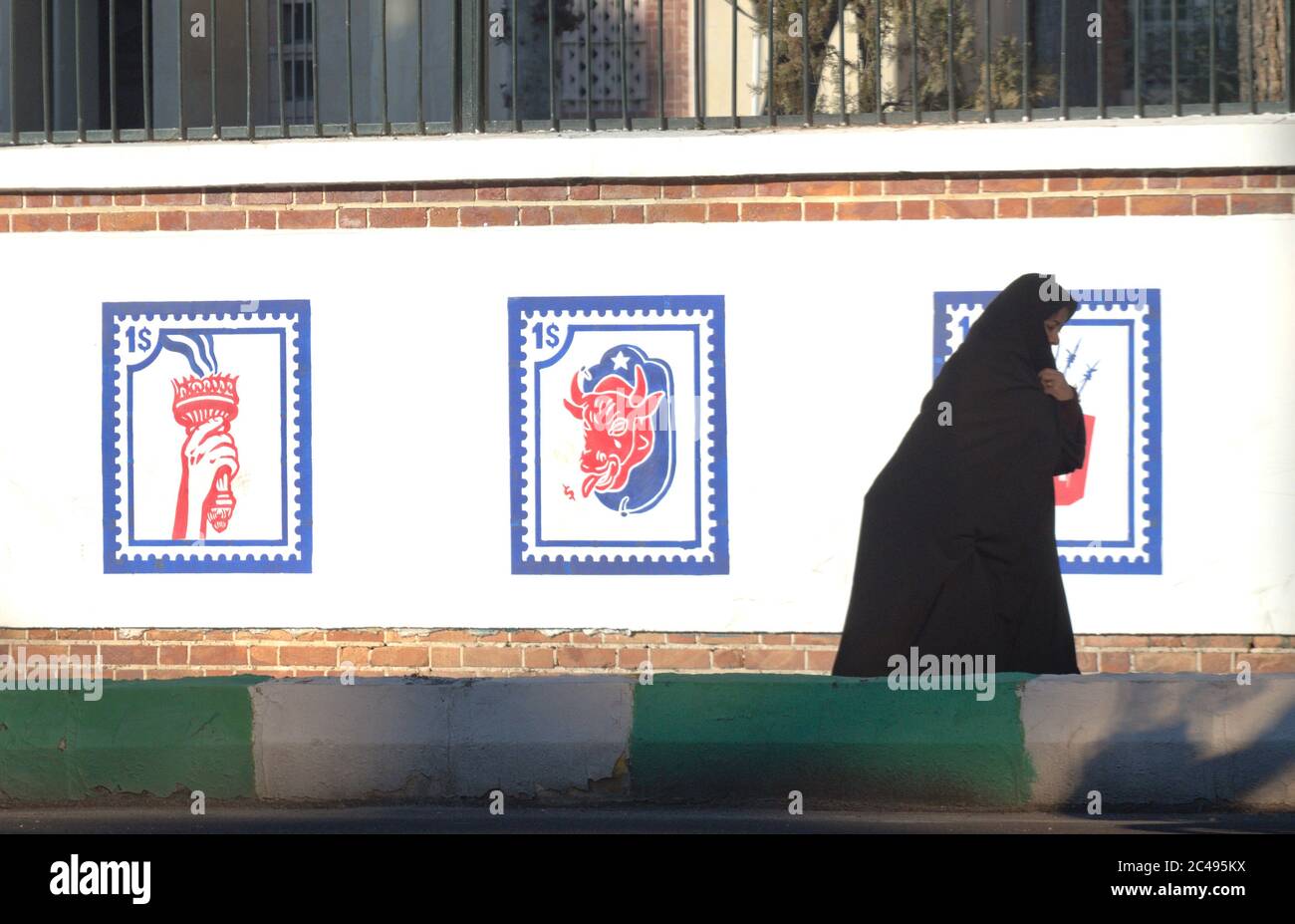 Iranian Muslim woman with chador in front of new anti-American murals outside former US Embassy in Tehran, Iran Stock Photo