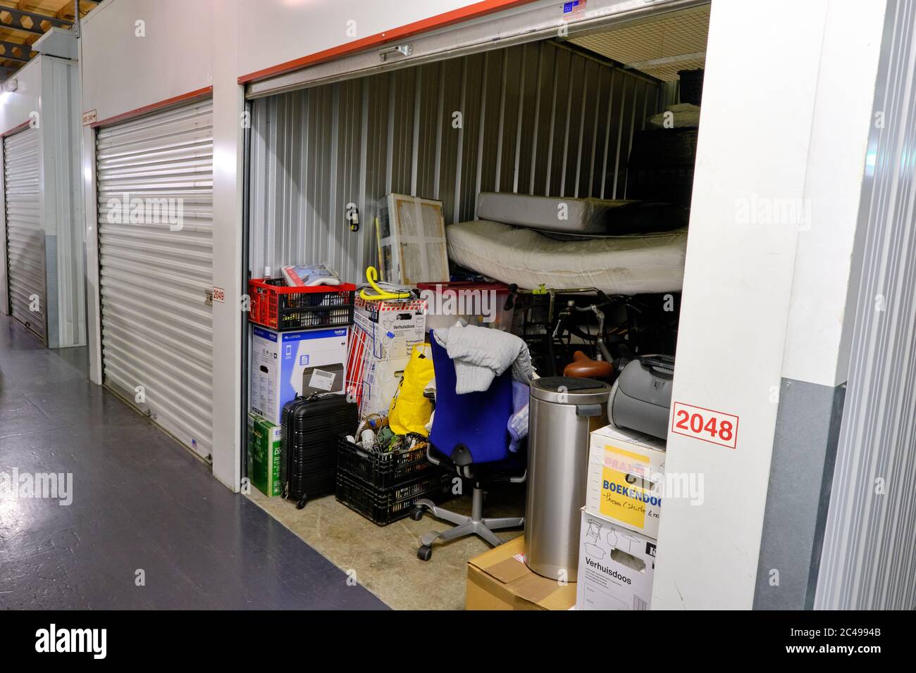 Amersfoort, the Netherlands,June,20,2020:Indoor storage unit with open door and household goods in a self storage facility. Rental Storage Units Stock Photo