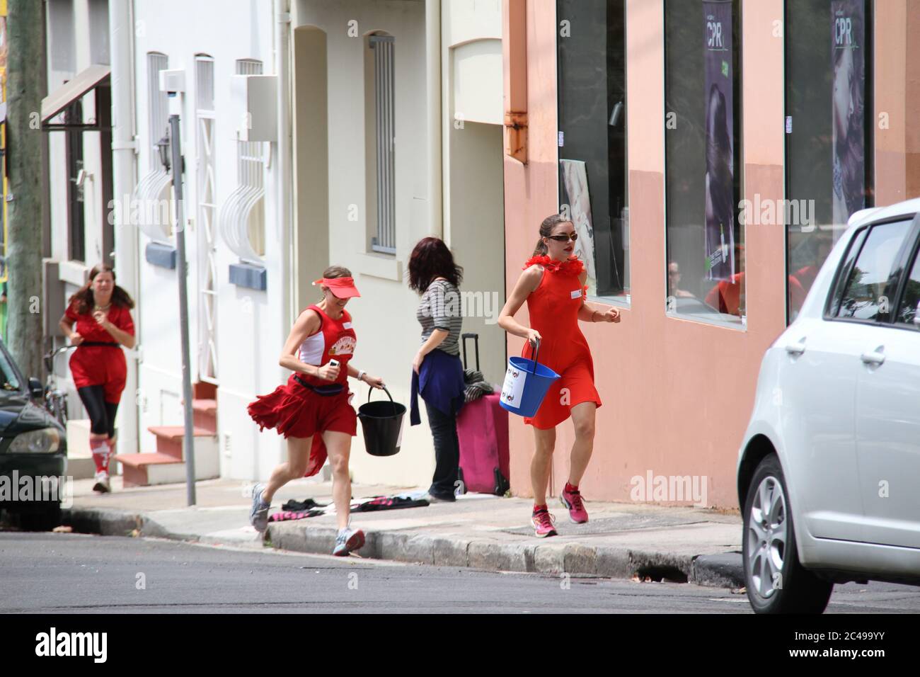 Sydney Thirsty Hash House Harriers 2014 red dress run participants run through the streets of Sydney in red dresses to collect money in buckets for Th Stock Photo