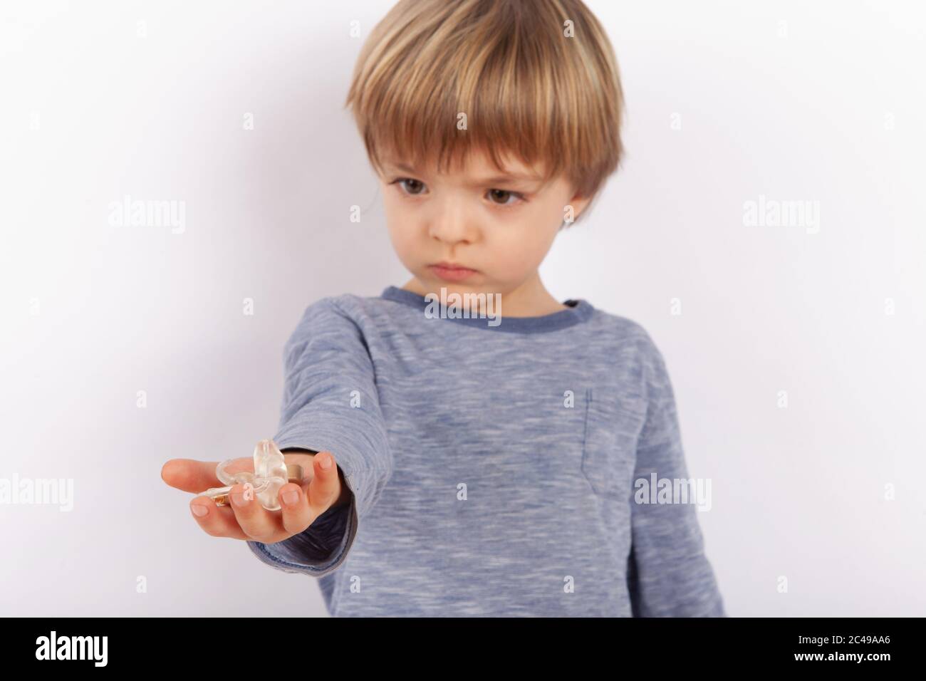 Cute small boy holding hearing aids on his palm. Focused on the hearing aid. Stock Photo