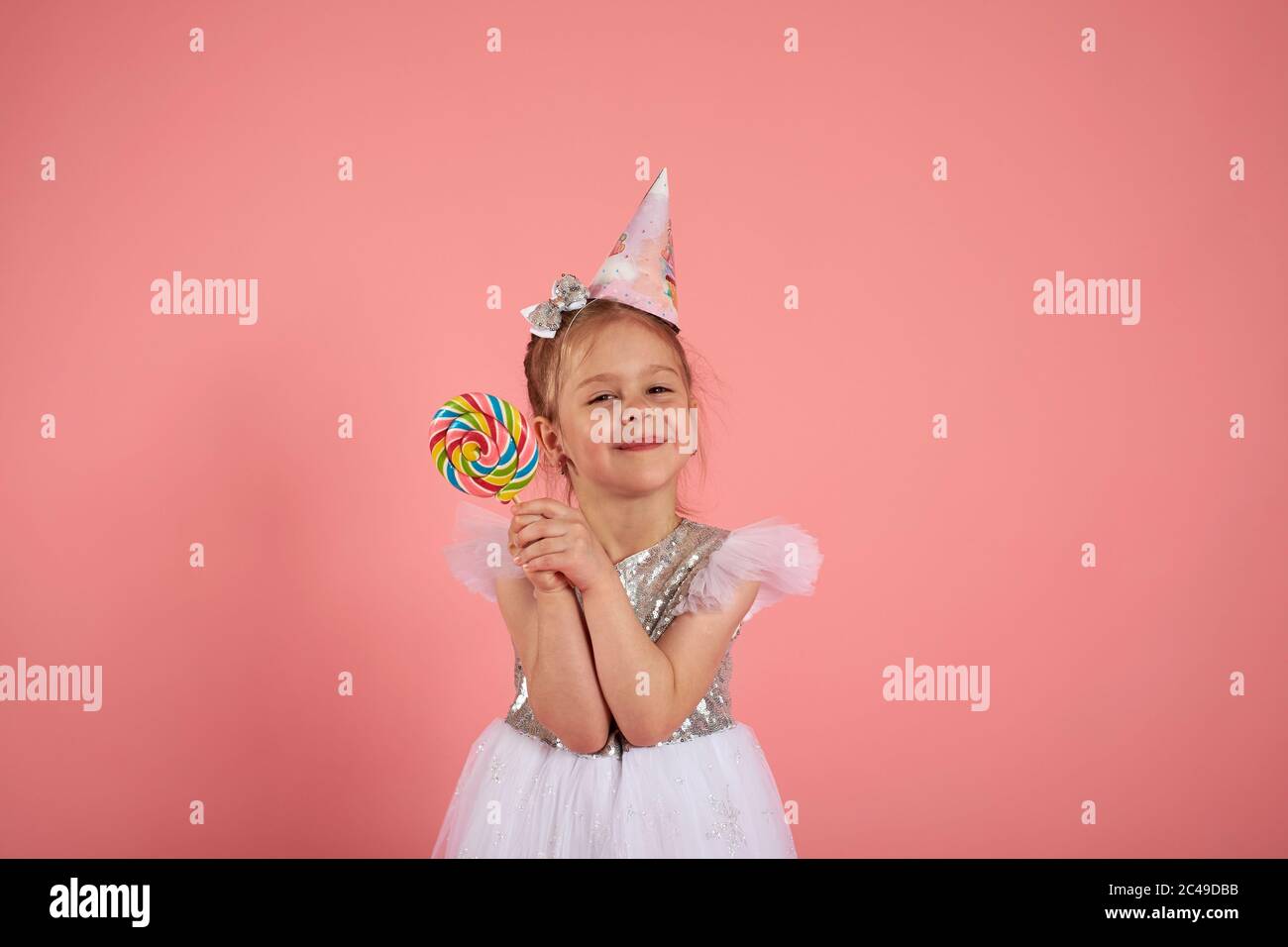 Happy smiling child with tasty lollipop having fun over pink background Stock Photo