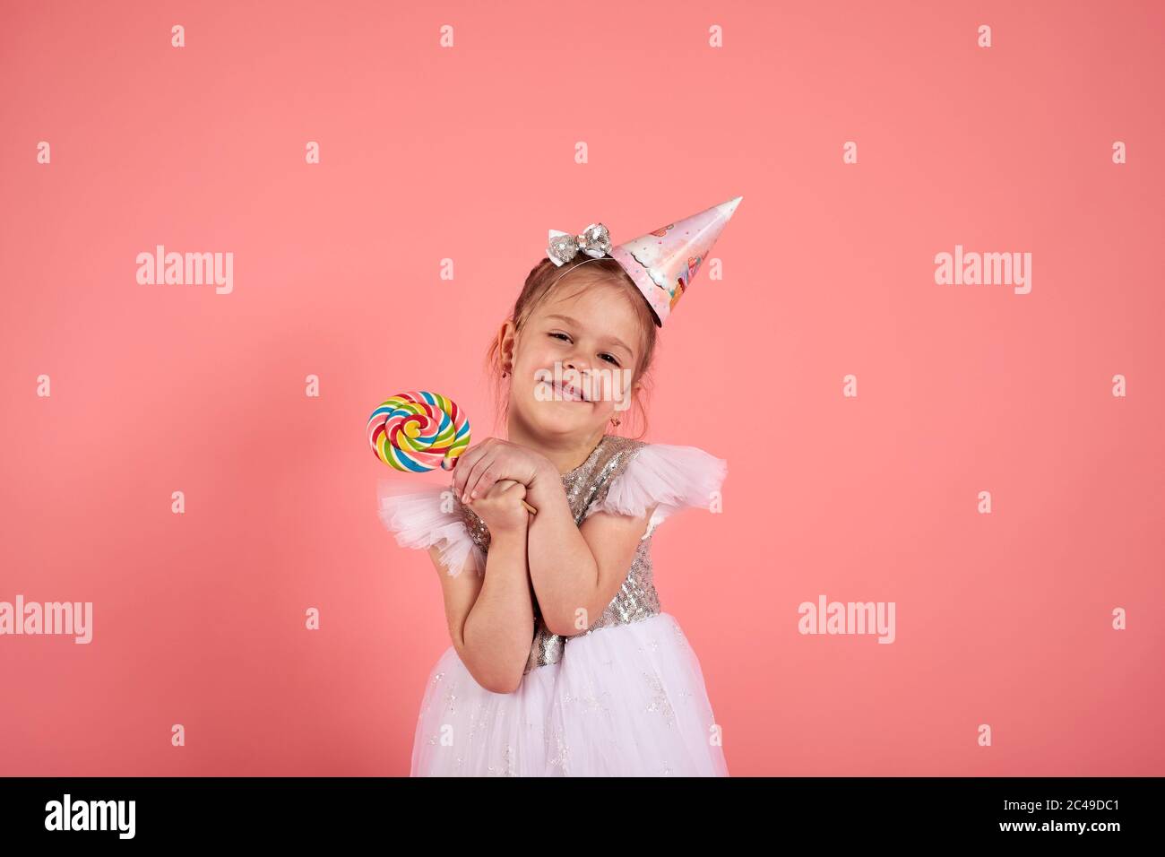 Happy smiling child with tasty lollipop having fun over pink background Stock Photo