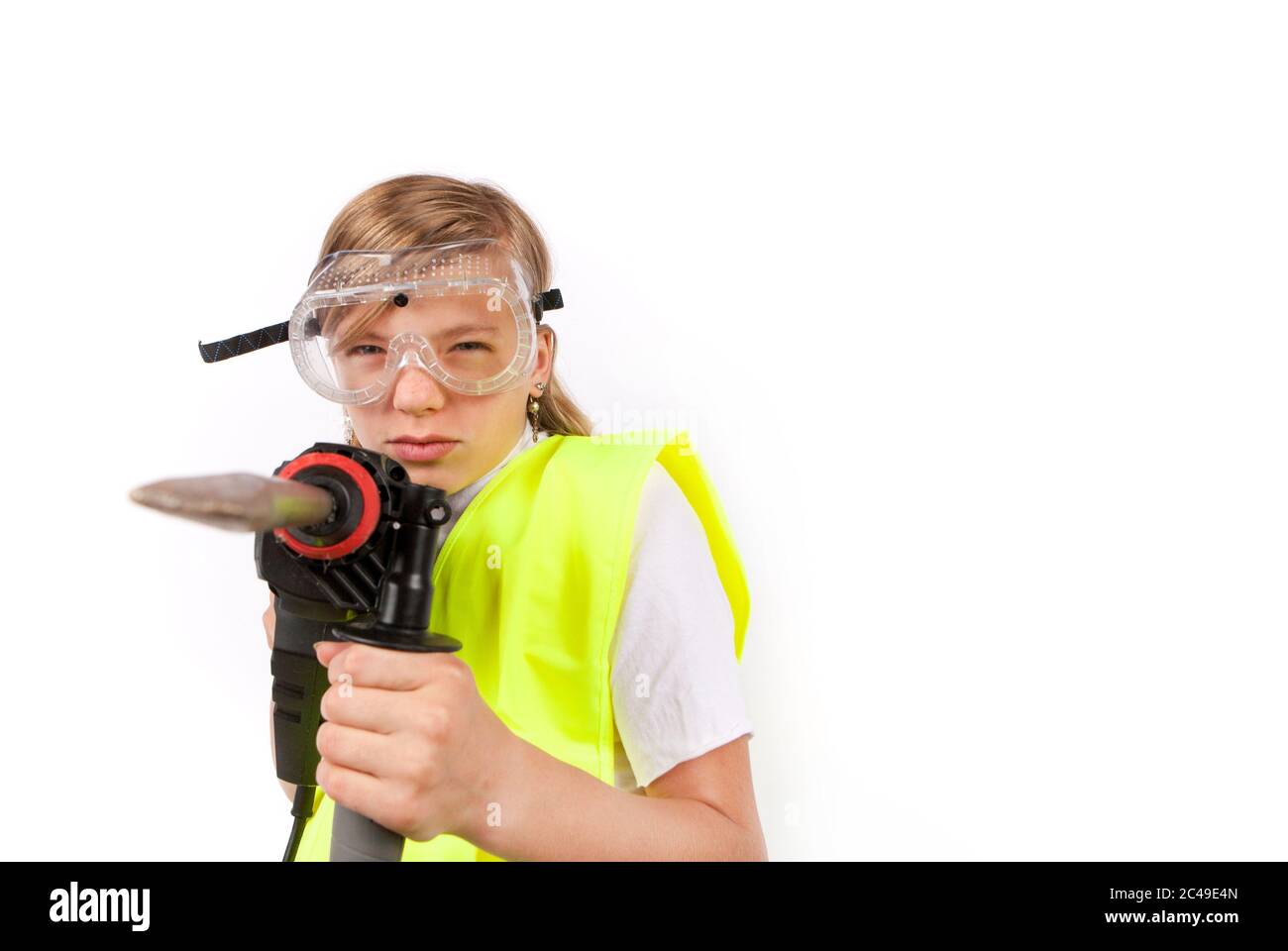 Cute young girl wearing safety vest and safety goggles posing with a rotary hammer Stock Photo