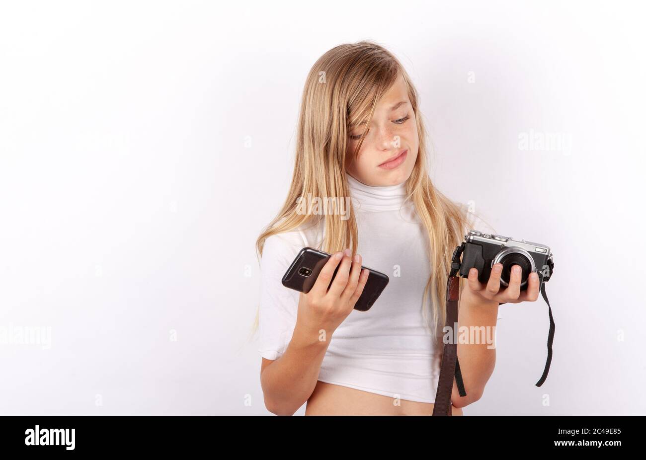 Young girl cant decide between smartphone and compact camera. Mobile phone versus classic camera concept Stock Photo