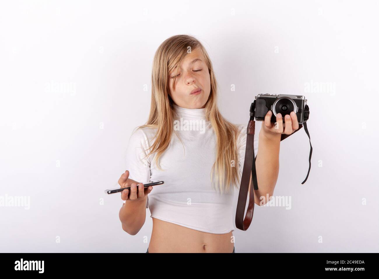 Teen girl cant choose between smartphone and compact camera. Mobile phone versus classic camera concept Stock Photo