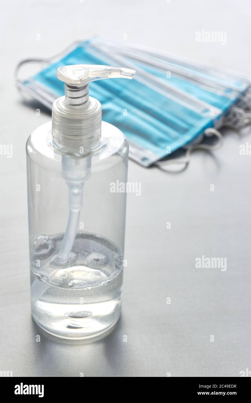 Plastic bottle of antibacterial hand sanitizer gel for hand hygiene coronavirus protection and blue face masks. Vertical image with copy space. Stock Photo