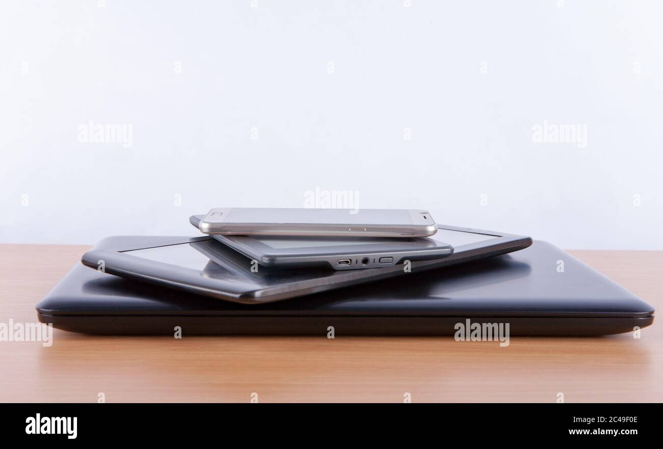Stack of electronic gadgets on a table - notebook, tablet, ebook reader ...