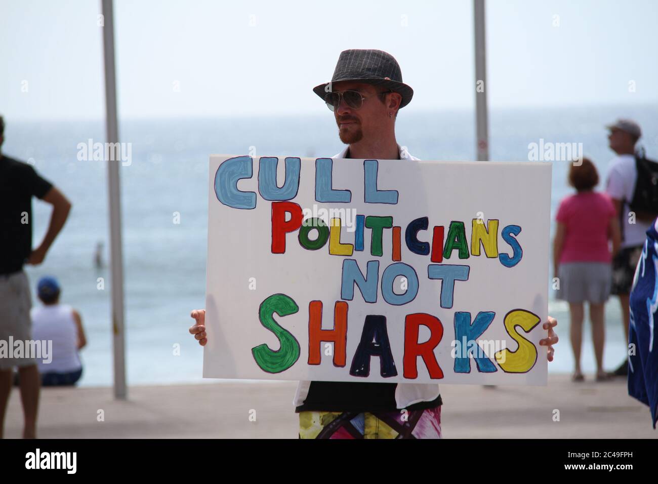 A protester directs people to the shark rally at Manly Beach. He holds ...
