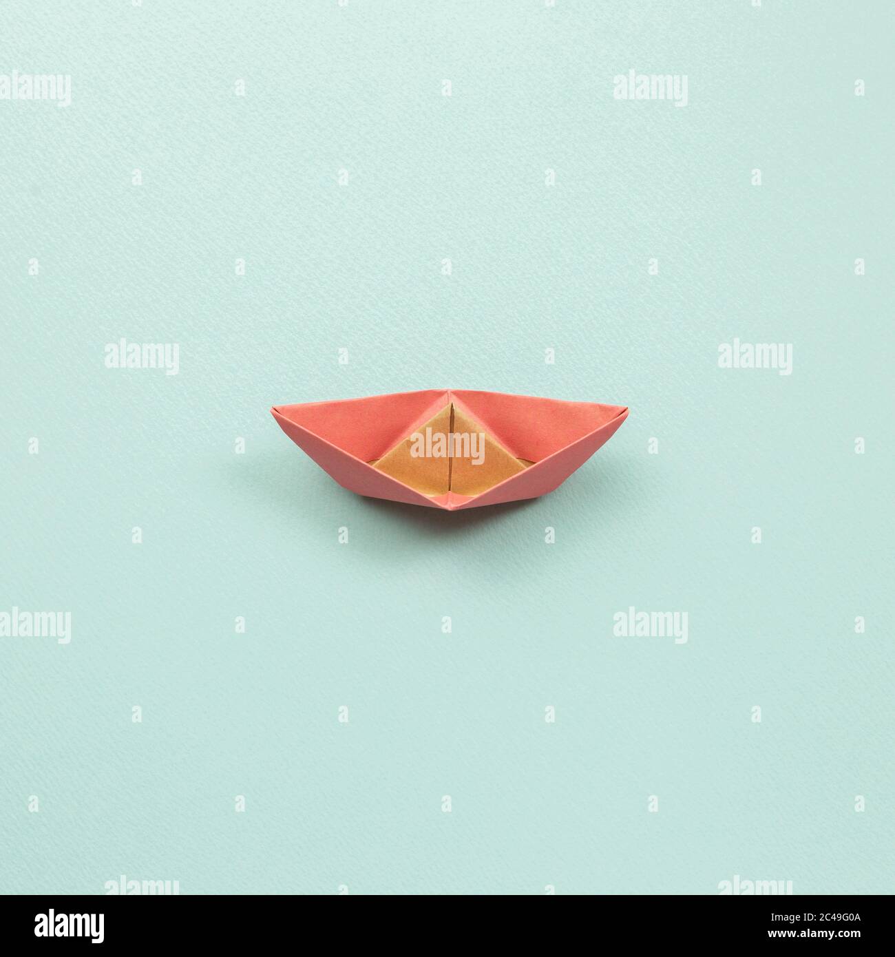 Pink paper ship on blue background. top view Stock Photo