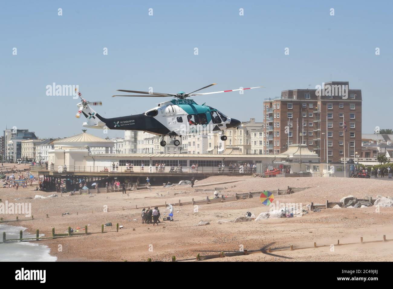 Worthing UK 25th June 2020 - An Air Ambulance lands on Worthing beach today as it attends an incident with the emergency services. Police have said that a woman believed to be in her 50s has died after suffering a medical incident on the beach  : Credit Simon Dack / Alamy Live News Stock Photo