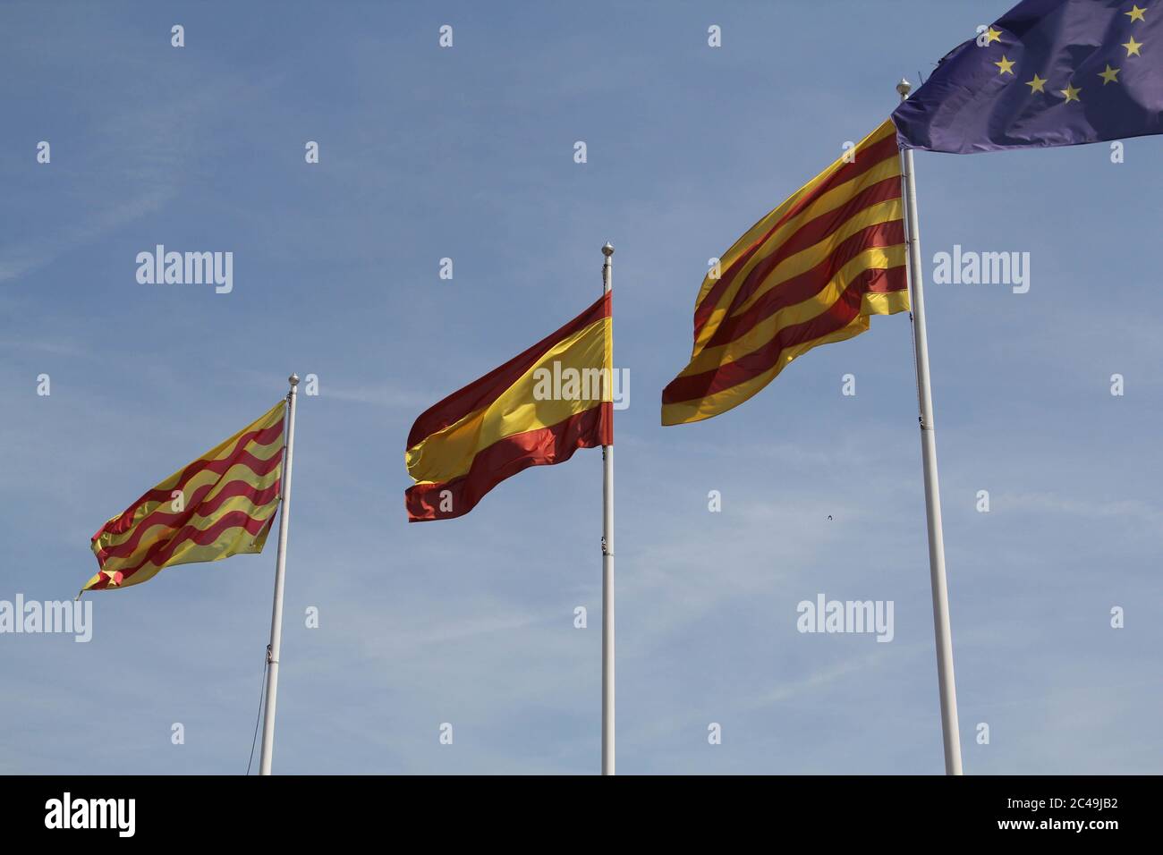 Flags of Spain, Catalonia, and the European Union waving in the sky Stock Photo