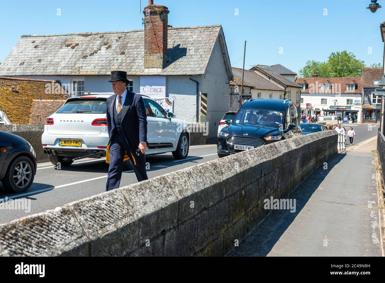 Fordingbridge, New Forest, Hampshire, UK, 25th June 2020. Mid-summer heatwave peaks making it the hottest day with the highest UV levels so far this year and a temperature over 32 degrees. A funeral cortege makes its way over the bridge in the blistering heat of the midday sun. Credit: Paul Biggins/Alamy Live News Stock Photo