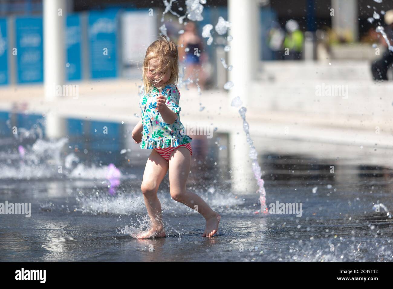 Three year old girl having fun in water fountains, Centenary Square, Birmingham UK Stock Photo