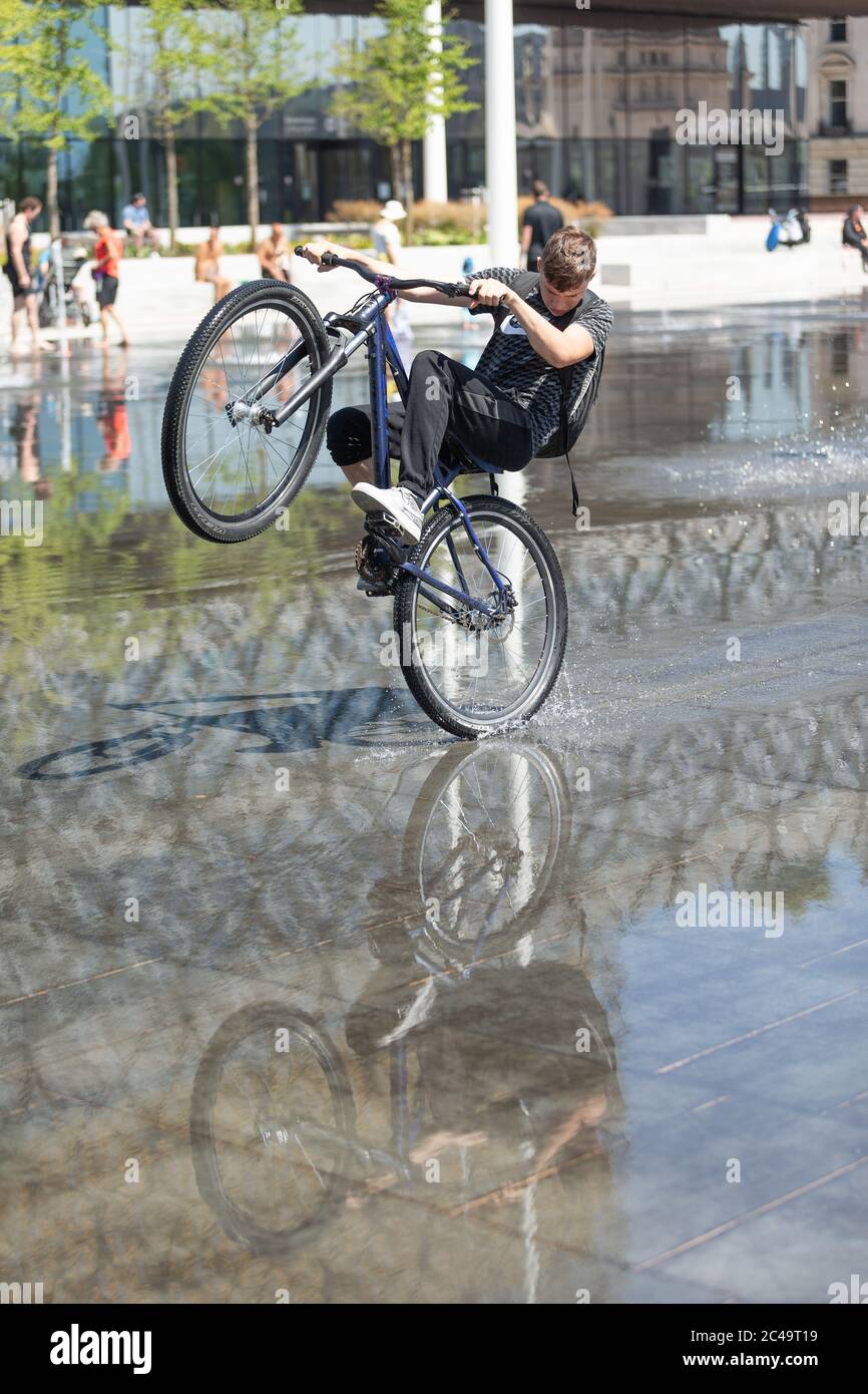 Boys doing wheelies tricks on bikes in fountains, UK Stock Photo Alamy