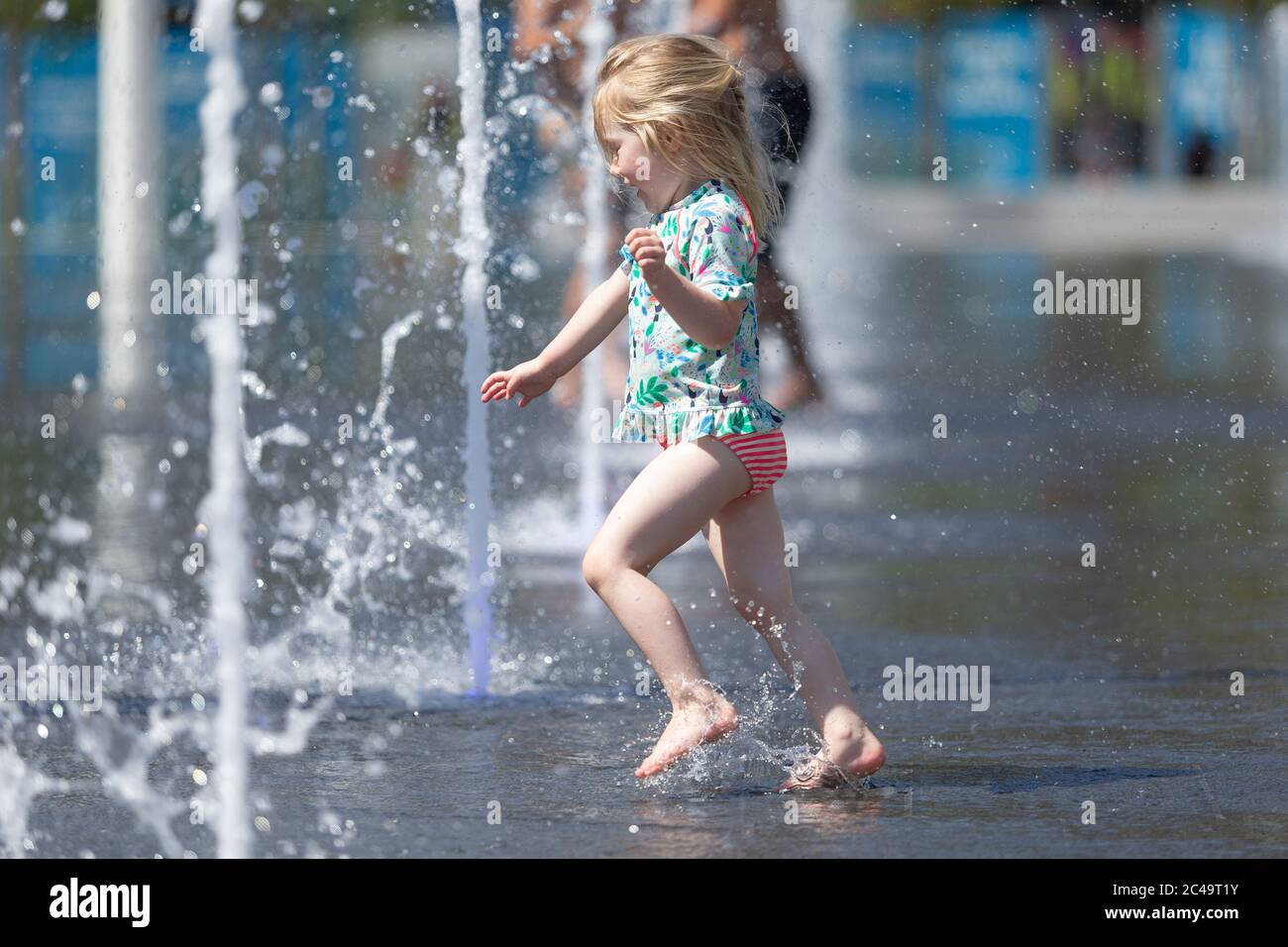 Three year old girl having fun in water fountains, Centenary Square, Birmingham UK Stock Photo