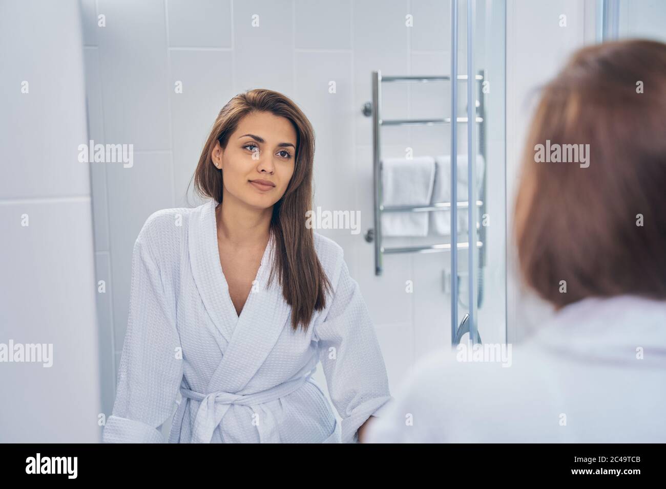 Beautiful young woman looking in the mirror Stock Photo - Alamy