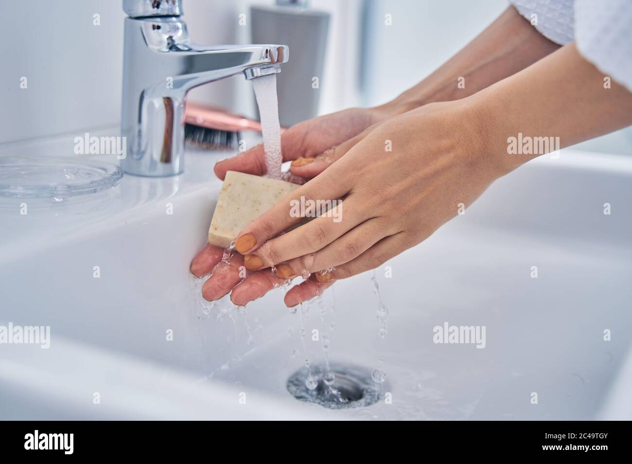 Young woman washing hands with soap in bathroom Stock Photo - Alamy