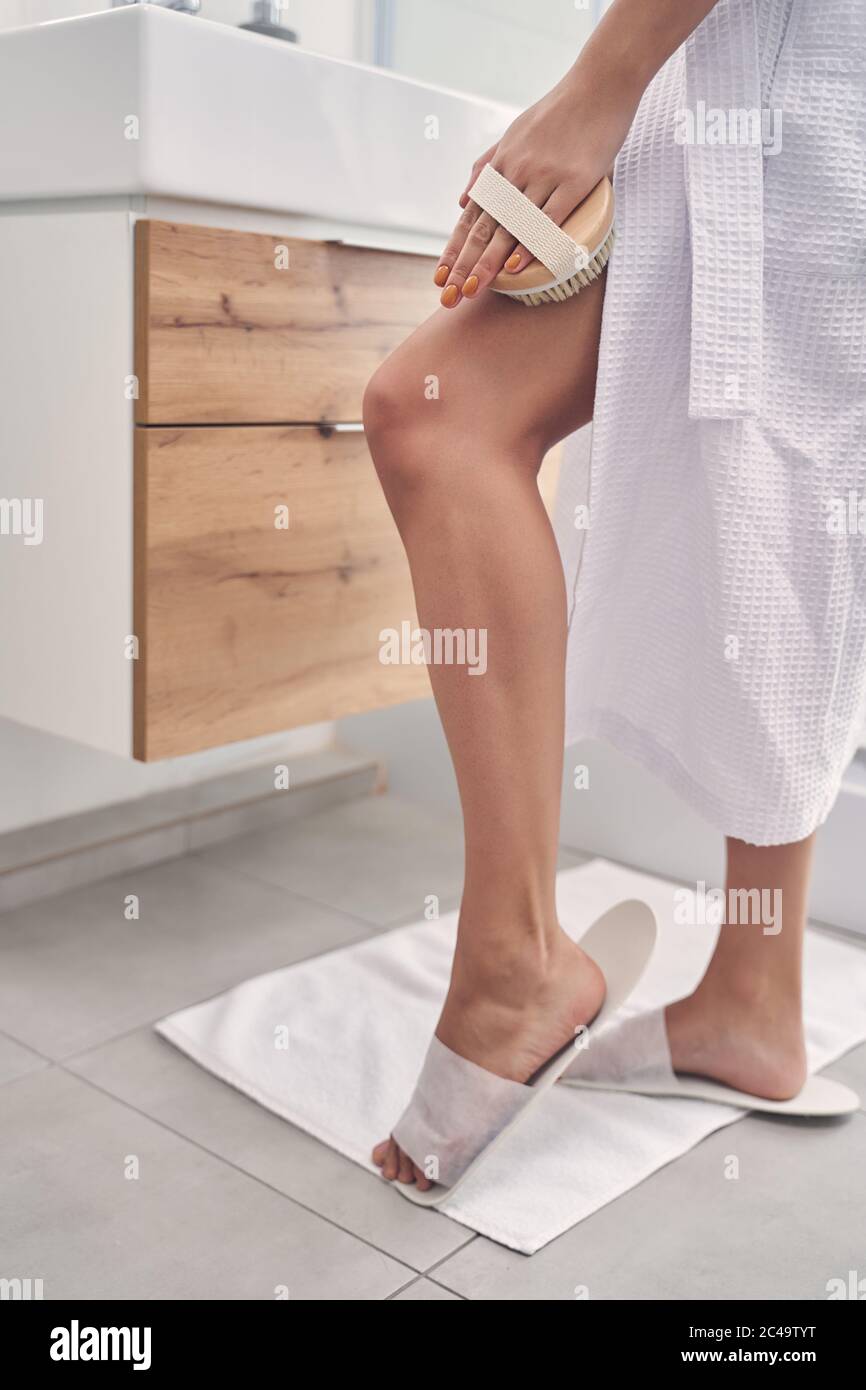 Young woman brushing dry skin with a naturalbristle brush Stock Photo