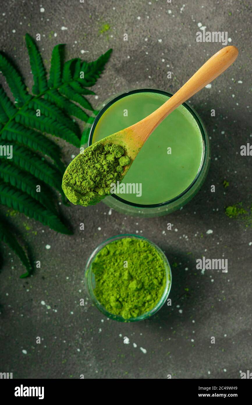 selective focus, Japanese green matcha tea with milk, with a wooden spoon and foliage on a dark background Stock Photo
