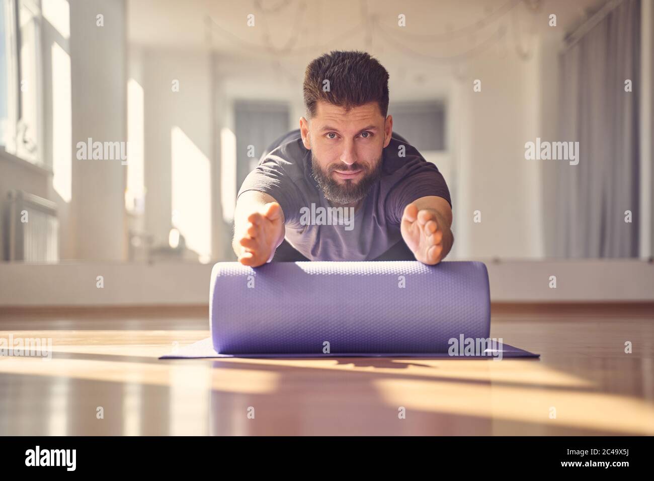 Bearded young man doing exercise with yoga roller block Stock Photo