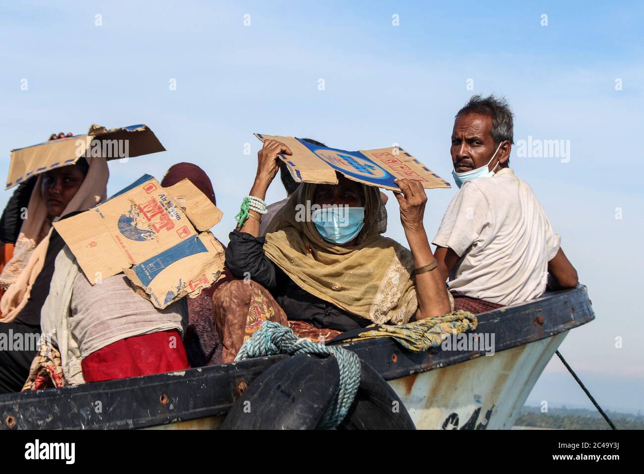 Aceh Utara, Indonesia. 25th June, 2020. Rohingya people seen on a stranded wooden boat using box papers to protect themselves from the sun 1 kilometre from the coast in North Aceh Regency.According to local officials, as many as 94 Rohingyas were found by Acehnese fishermen stranded in the middle of the sea waters 1 kilometre from the coast off Aceh Province using wooden boats. Credit: SOPA Images Limited/Alamy Live News Stock Photo