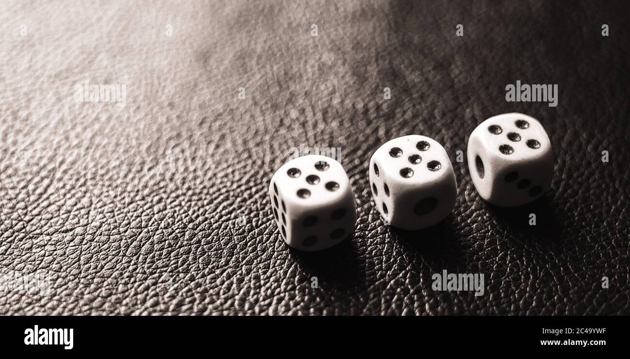 Three dices on the black table. BW photo Stock Photo