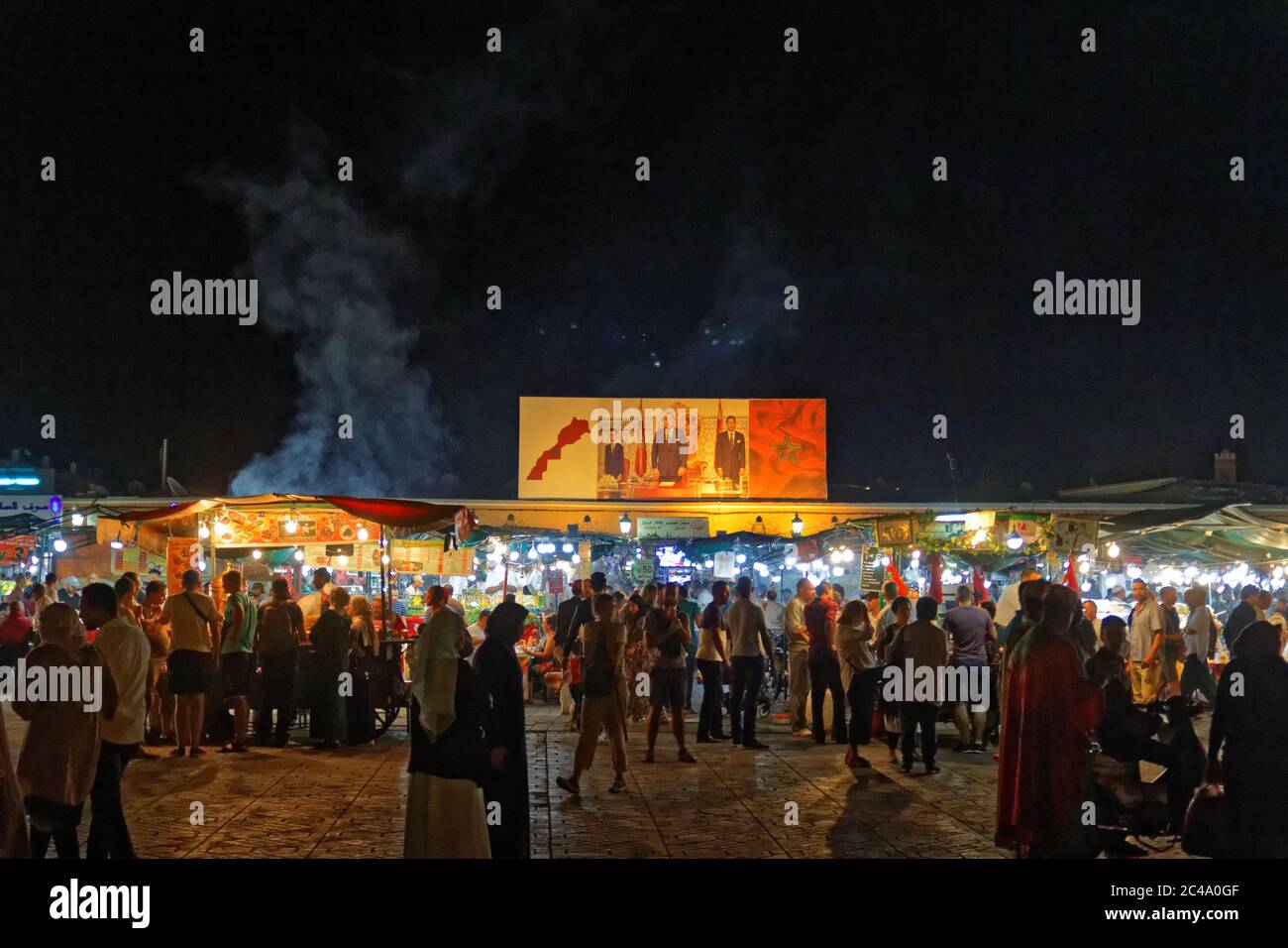 Marrakesh, Morocco,Okt 4,2018:People at night at food stands Jemaa el Fna Square. Square is UNESCO World Heritage.Big poster king Mohammed VI. Stock Photo
