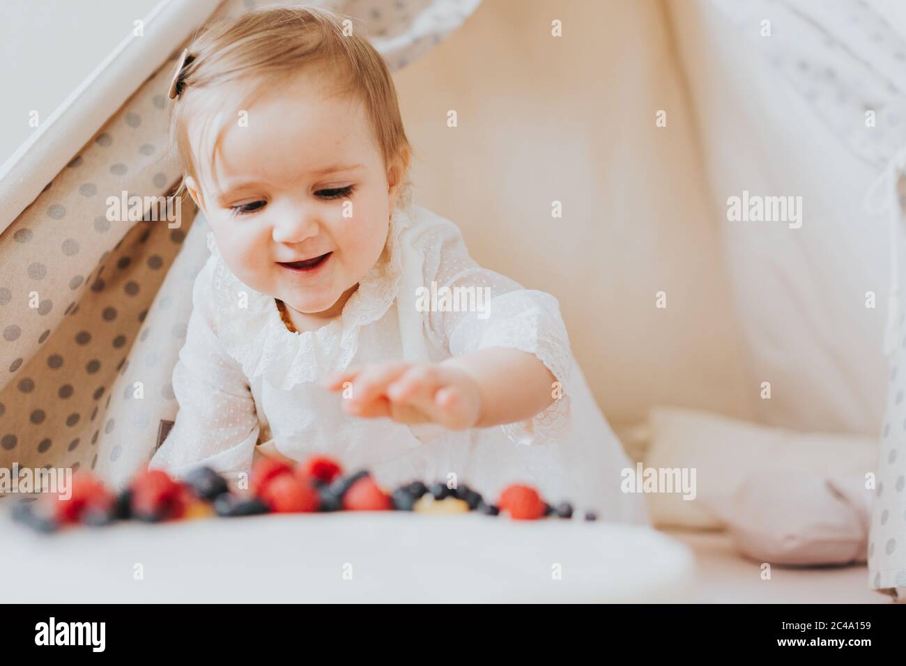 Baby girl dressed up in bright clothing celebrates her one year birthday at home Stock Photo