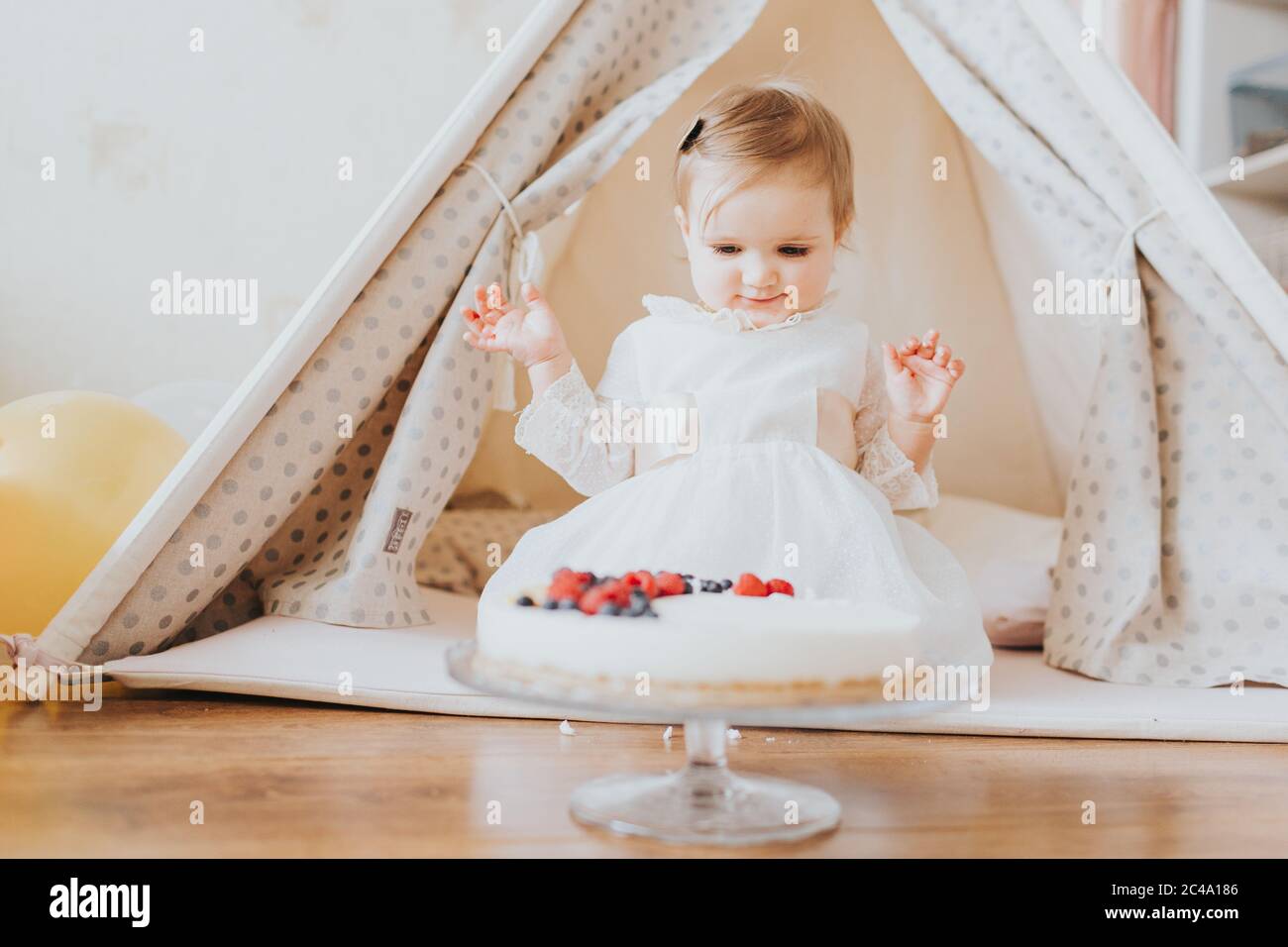 Baby girl dressed up in bright clothing celebrates her one year birthday at home Stock Photo