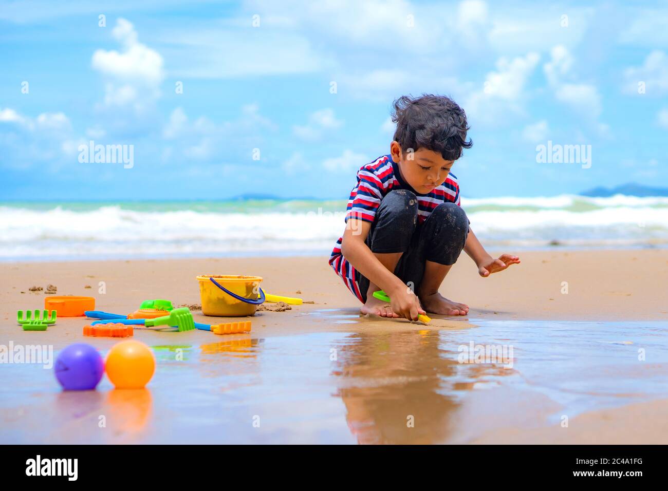 Little asian boy play with toy and sand on the beach. Stock Photo