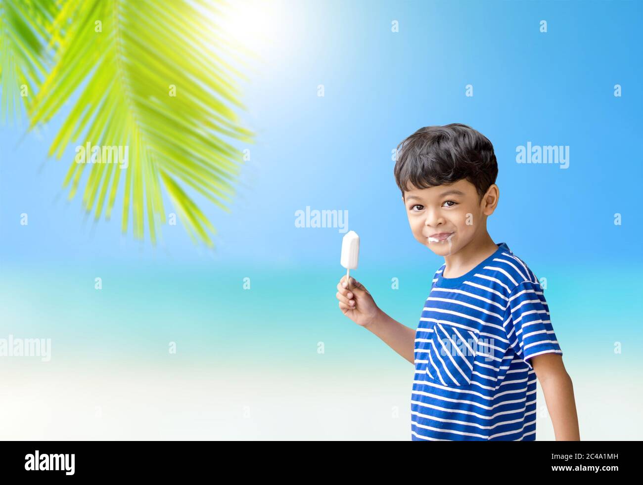 Little Thai boy eating white chocolate Ice cream  against sunshine light and blue sky in summer time. Stock Photo